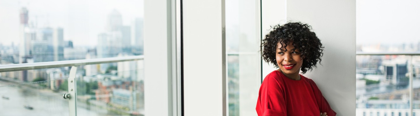 Woman in red dress leaning against a window