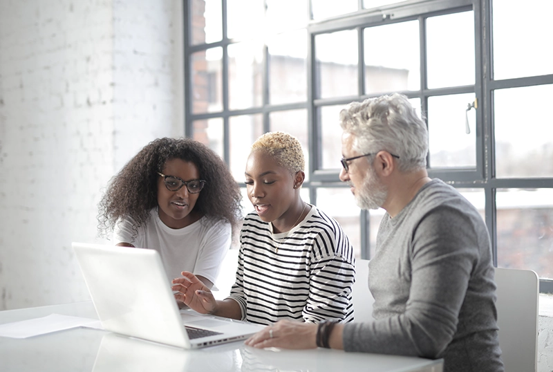 Three people looking at a laptop